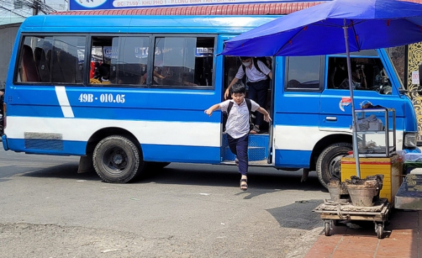 Học sinh trường tiểu học Long Bình Tân (TP Biên Hòa, Đồng Nai) nhảy xuống từ xe đưa đón, ngày 15/2/2023. Ảnh: Phước Tuấn