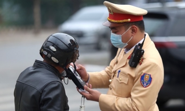 2023년 11월 하노이에서 경찰관이 오토바이 운전자의 호흡으로 알코올 농도를 확인하고 있습니다. 사진 제공: VnExpress/Hoang Phong
